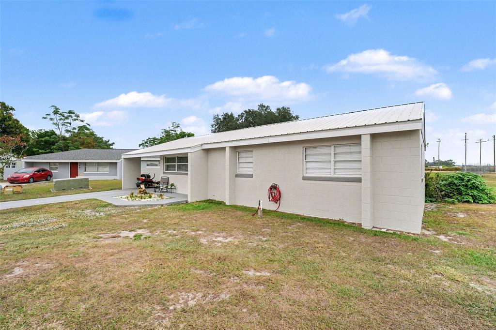 A light-colored concrete block house with a metal roof and a small front patio — 45 QUEENS COURT, FROSTPROOF, FL