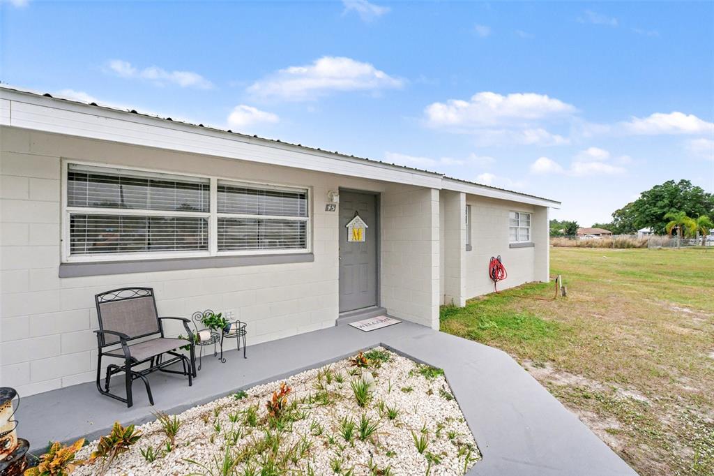 A single-story house exterior with a gray front door, a porch, and a gravel garden — 45 QUEENS COURT, FROSTPROOF, FL