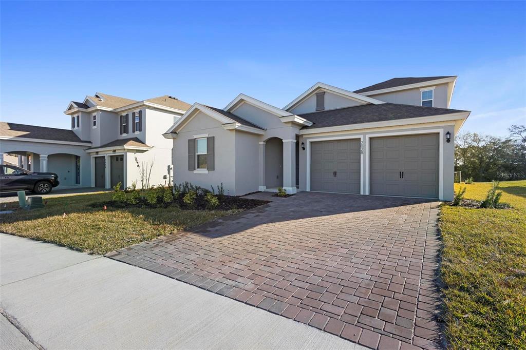 A light-colored single-story house with a two-car garage and a paved driveway — 2028 KEYSTONE PASS BOULEVARD, MINNEOLA, FL
