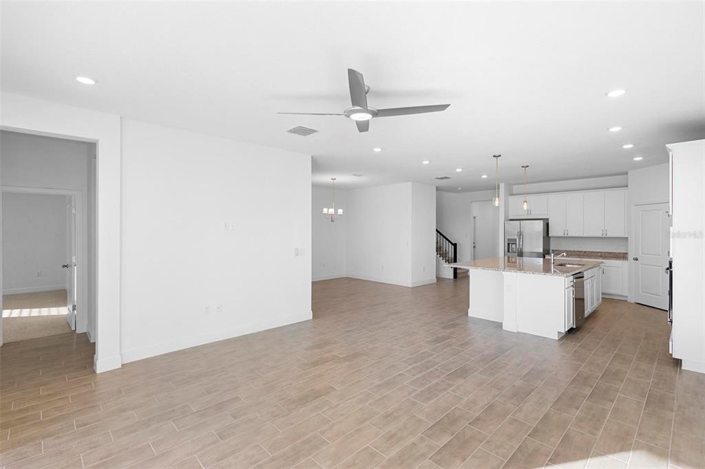 An open-concept kitchen and living area featuring white cabinetry, a kitchen island, and tile flooring — 2028 KEYSTONE PASS BOULEVARD, MINNEOLA, FL