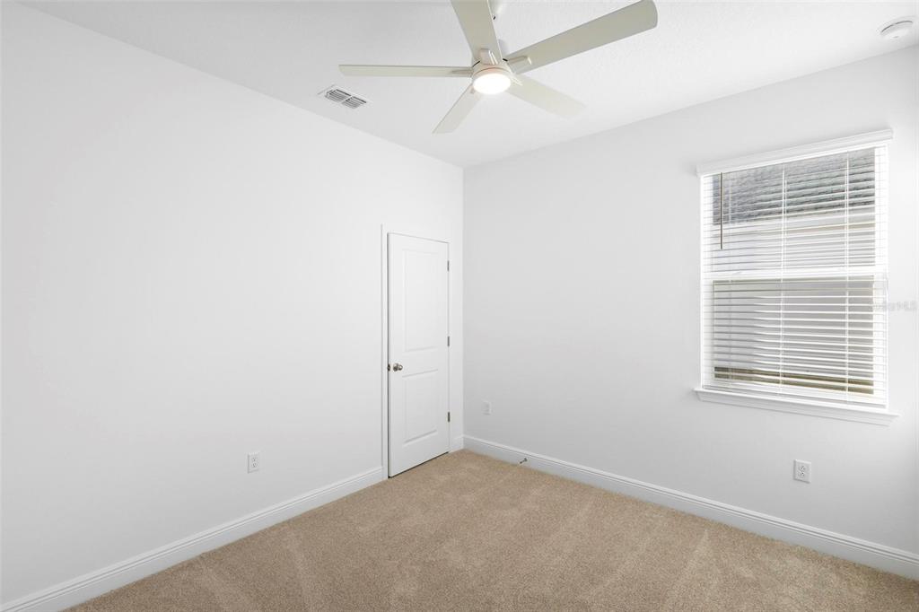 An empty bedroom with white walls, beige carpet, a ceiling fan, and a single window — 2028 KEYSTONE PASS BOULEVARD, MINNEOLA, FL