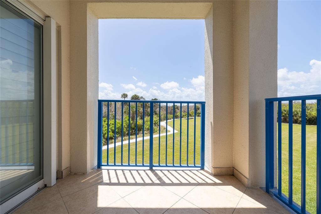 A covered balcony with tiled flooring and blue metal railings overlooks a grassy lawn — 5300 S ATLANTIC AVENUE UNIT 6-207, NEW SMYRNA BEACH, FL