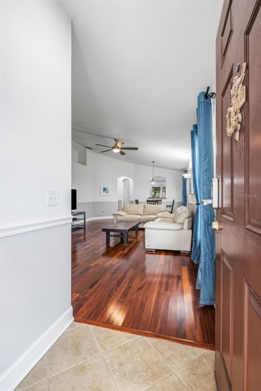 An entryway opens into a living room with hardwood floors, white walls, and vaulted ceilings — 7861 TUSCANY WOODS DRIVE, TAMPA, FL