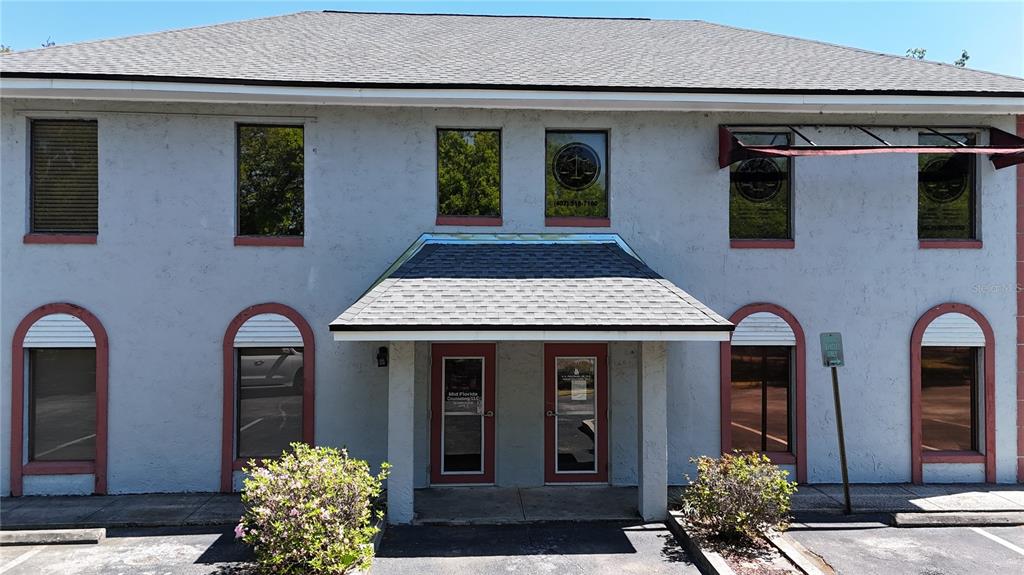 A two-story commercial building with a central entrance, gray stucco walls, and arched windows — 1400 W OAK STREET UNIT F, KISSIMMEE, FL