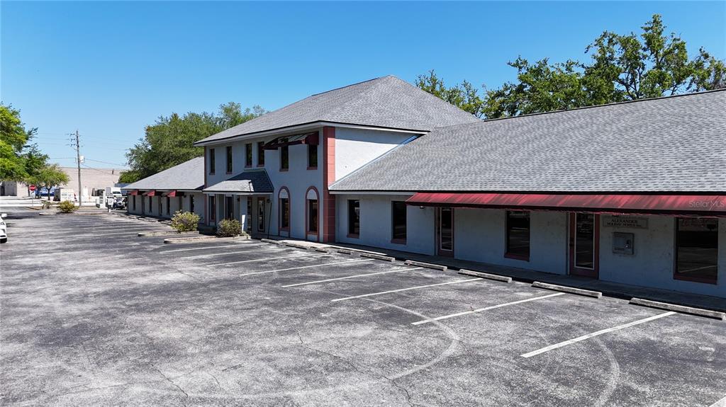 An exterior view of a multi-tenant commercial building with a large asphalt parking lot — 1400 W OAK STREET UNIT F, KISSIMMEE, FL