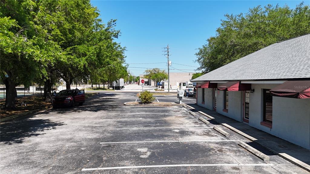 An asphalt parking lot sits in front of a single-story building with red awnings — 1400 W OAK STREET UNIT F, KISSIMMEE, FL
