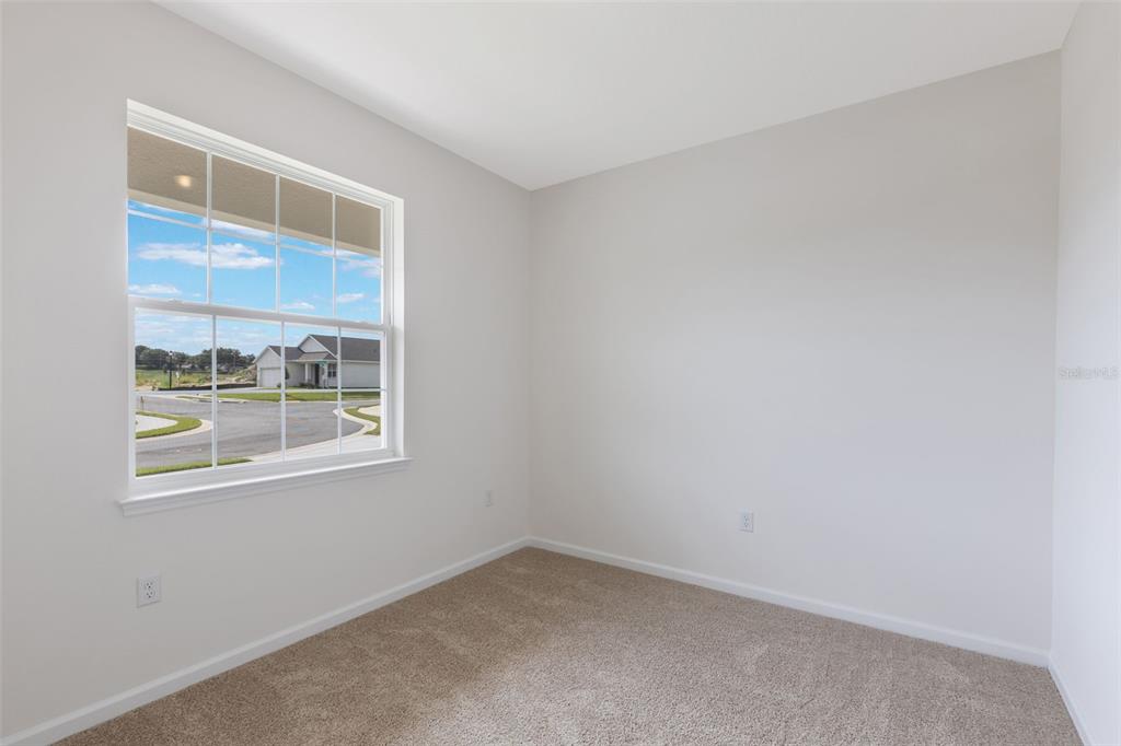 An empty bedroom with beige carpet, white walls, and a window overlooking a suburban street — 3788 WATERCLIFF CIRCLE, GRAND ISLAND, FL