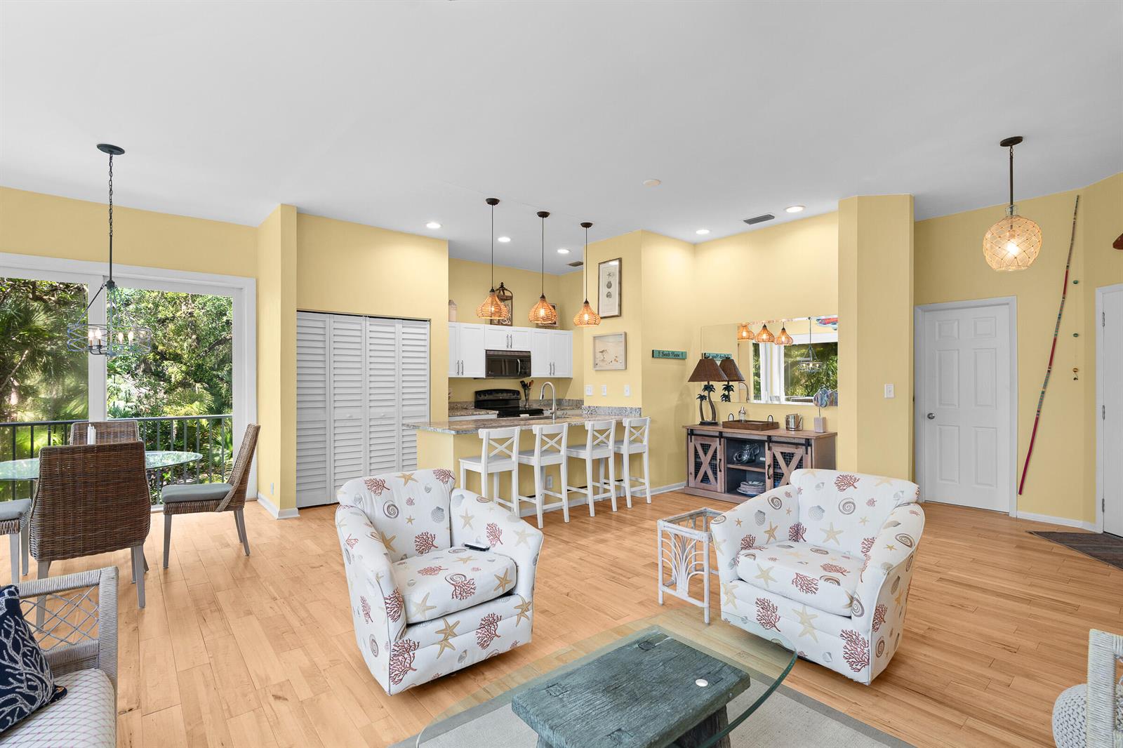 An open-concept living and kitchen area features yellow walls, light wood flooring, and coastal decor — VERO BEACH, FL