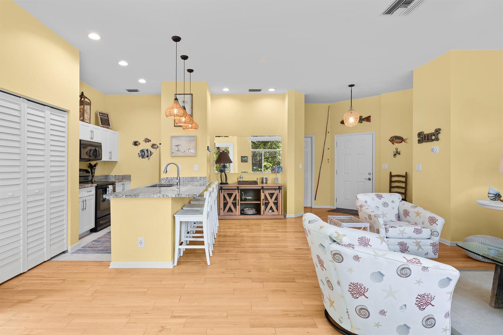 A kitchen with a breakfast bar and living area featuring yellow walls and light flooring — VERO BEACH, FL