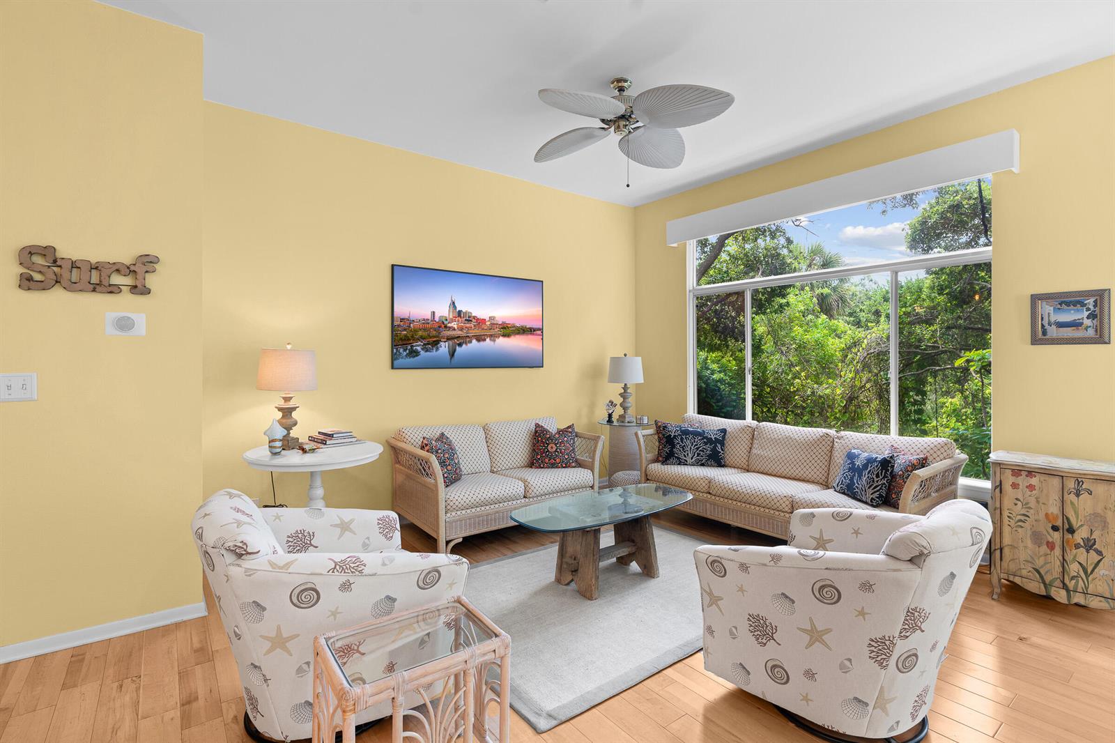 A living room features yellow walls, wicker furniture, patterned armchairs, and a large window view — VERO BEACH, FL
