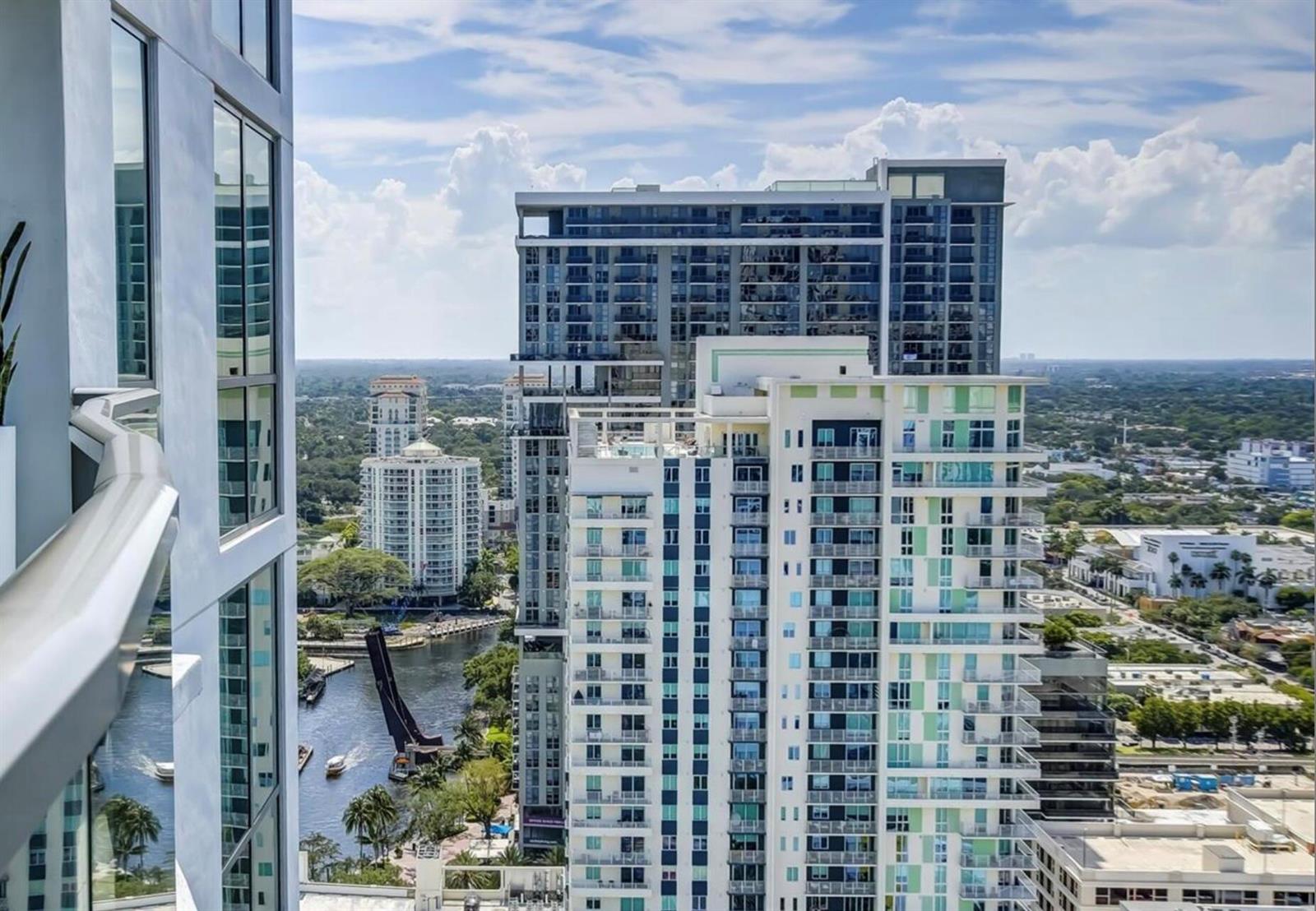 An elevated view of modern high-rise apartment buildings overlooking a river and city landscape — 100 E Las Olas Boulevard # 2802, Fort Lauderdale FL 33301, FORT LAUDERDALE, FL