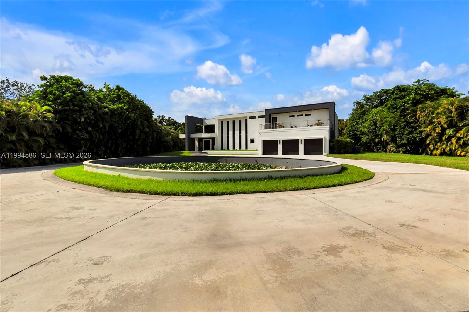 A modern two-story house features a circular driveway with a central lily pond — 13441 Mustang Trl, Southwest Ranches FL 33330, SOUTHWEST RANCHES, FL