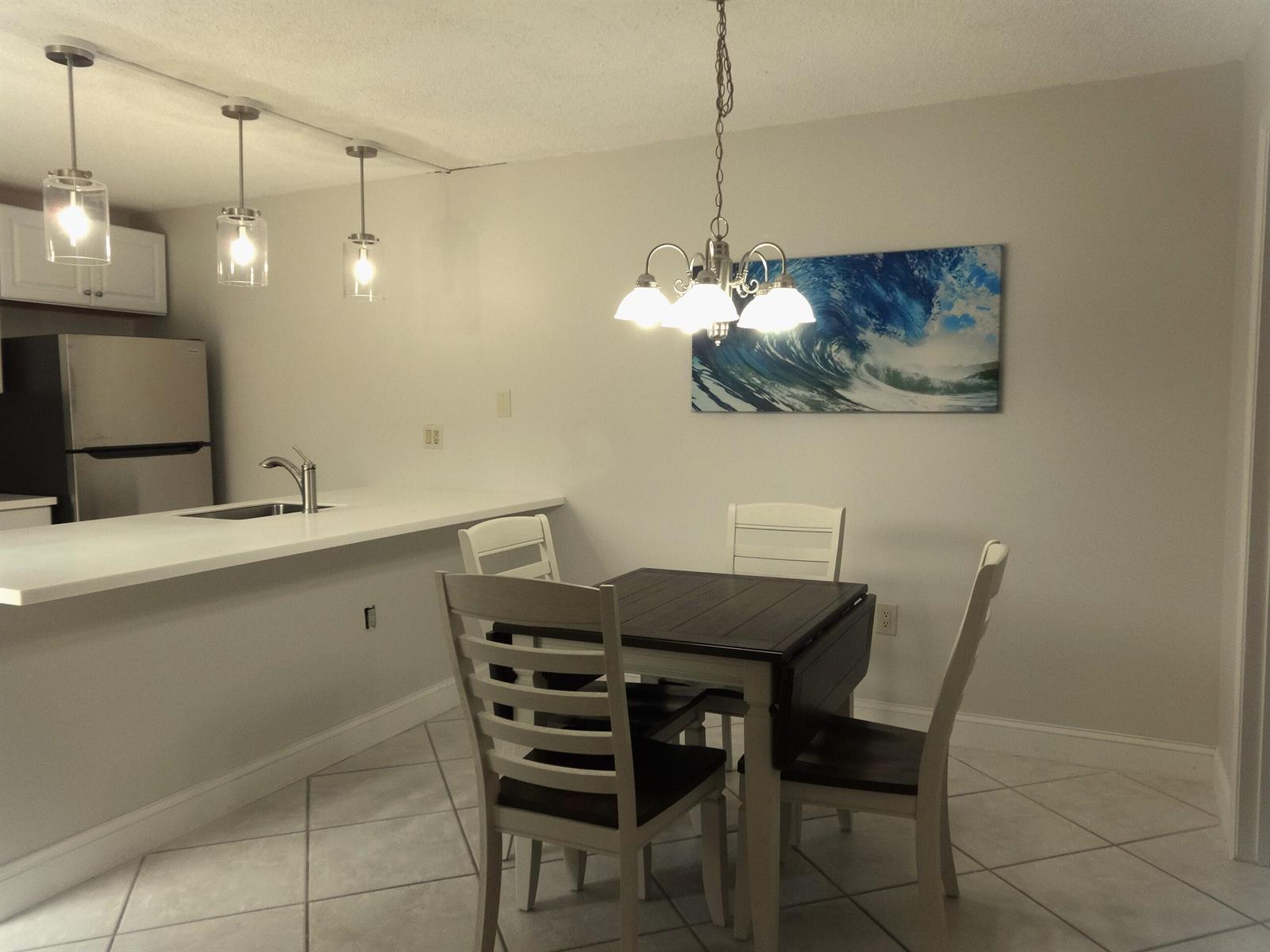 A dining area with a square table and chairs sits adjacent to a kitchen counter — 2914 29th Court, Jupiter FL 33477, JUPITER, FL