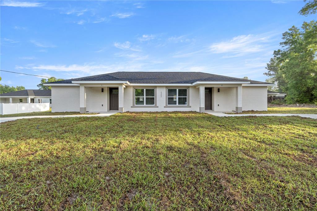A single-story duplex with a light-colored stucco exterior, dark roof, and two front entrances — 5349 NW 11TH STREET, OCALA, FL