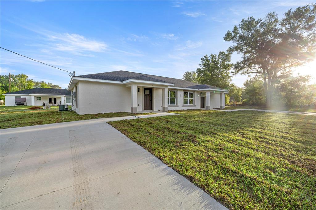 A single-story house with a light-colored stucco exterior and a concrete driveway — 5349 NW 11TH STREET, OCALA, FL