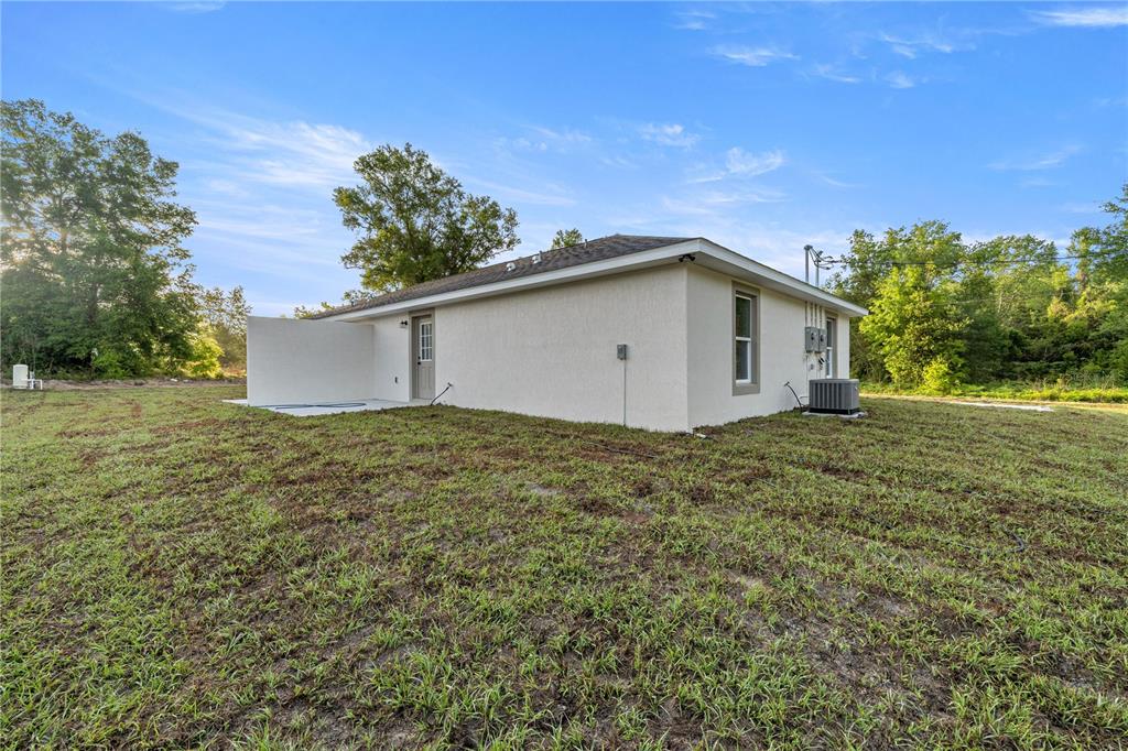 The exterior of a light-colored, single-story house features a small patio and a side door — 5349 NW 11TH STREET, OCALA, FL