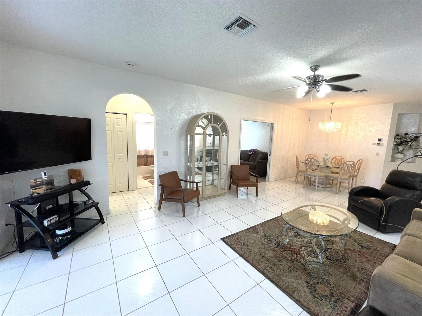 A living and dining area with white tile floors, an arched doorway, and a ceiling fan — 7941 Laina Lane # 2, Boynton Beach FL 33437, BOYNTON BEACH, FL