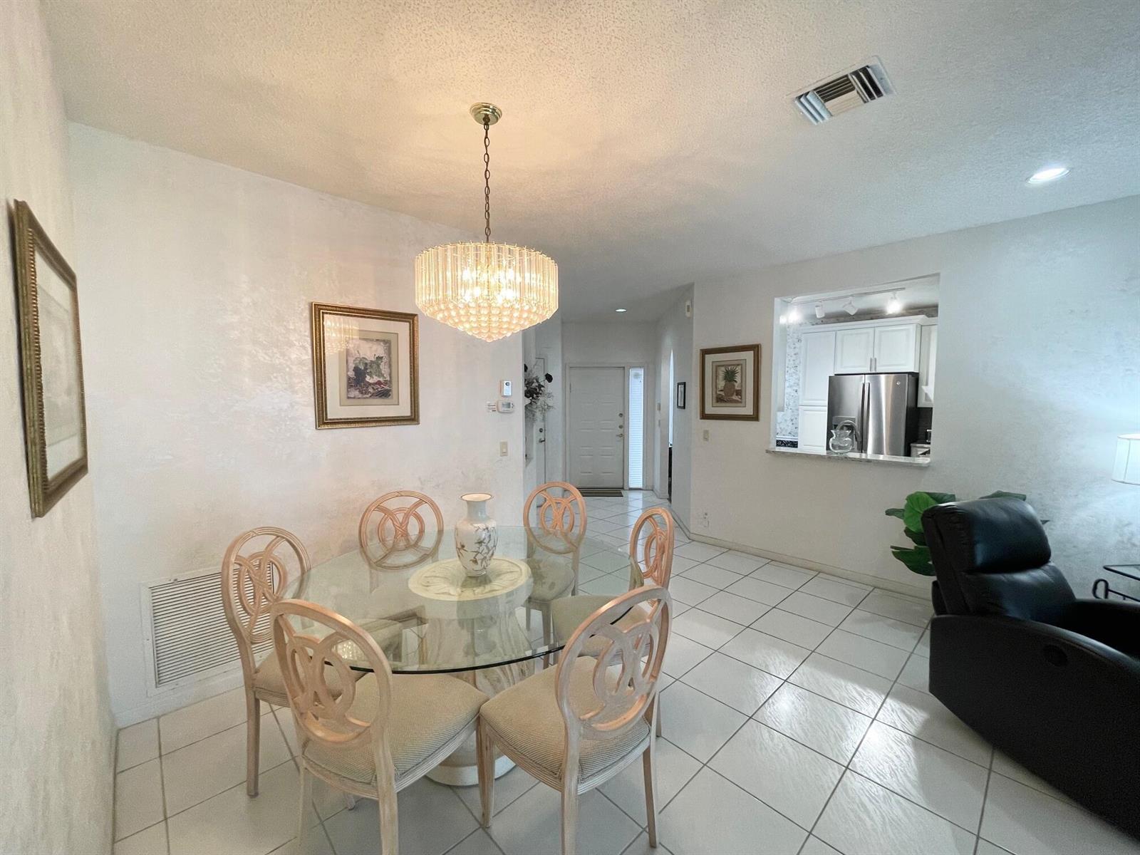 A dining area features a glass table, six chairs, and a crystal chandelier — 7941 Laina Lane # 2, Boynton Beach FL 33437, BOYNTON BEACH, FL