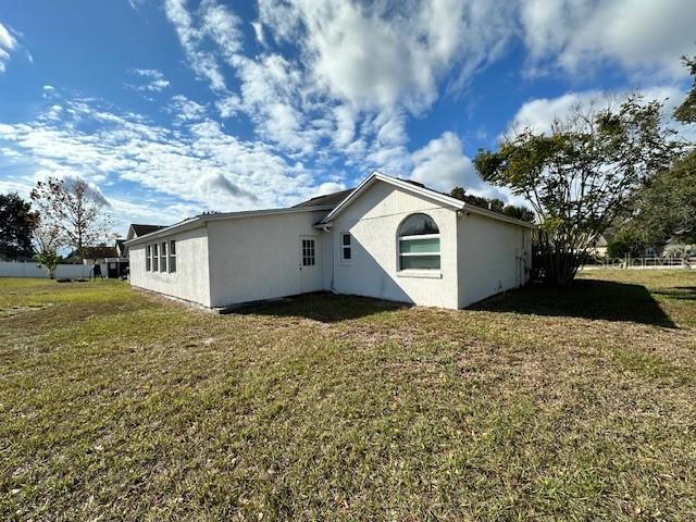 The exterior of a single-story white house with a gabled roof and a large yard — 233 VIA DEL SOL DRIVE, DAVENPORT, FL