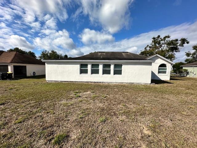 The exterior of a white stucco house with a dark roof and four windows — 233 VIA DEL SOL DRIVE, DAVENPORT, FL