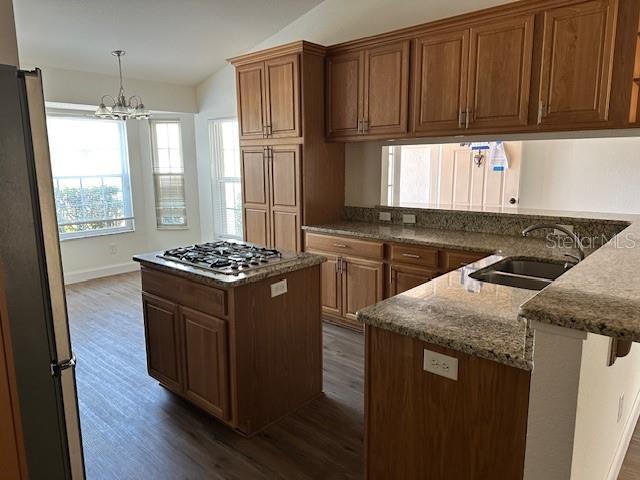 A kitchen features wood cabinets, granite countertops, a center island with a cooktop, and flooring — 233 VIA DEL SOL DRIVE, DAVENPORT, FL