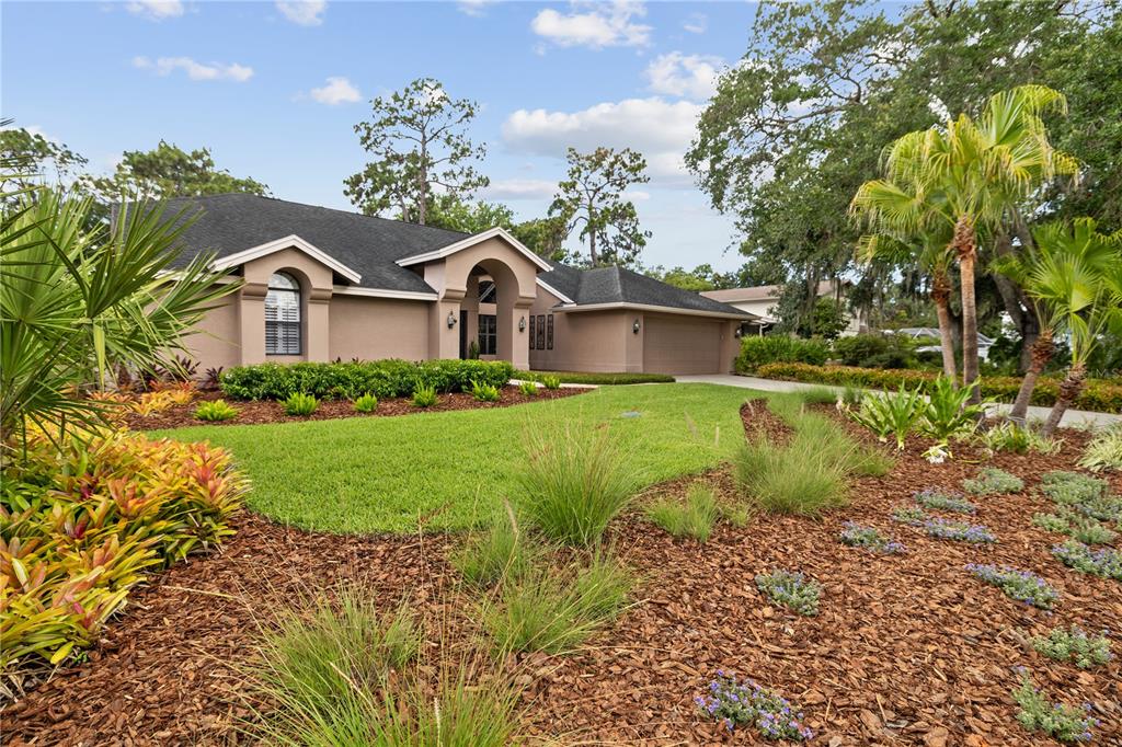 A single-story house with a tan exterior, dark roof, and landscaped front yard — 3372 BRIAN ROAD S, PALM HARBOR, FL