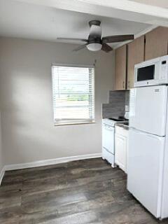 A small kitchen features light-colored cabinets, a white refrigerator, a stove, and wood-look flooring — 112 Lake Avenue # 12, FL 33460, FL
