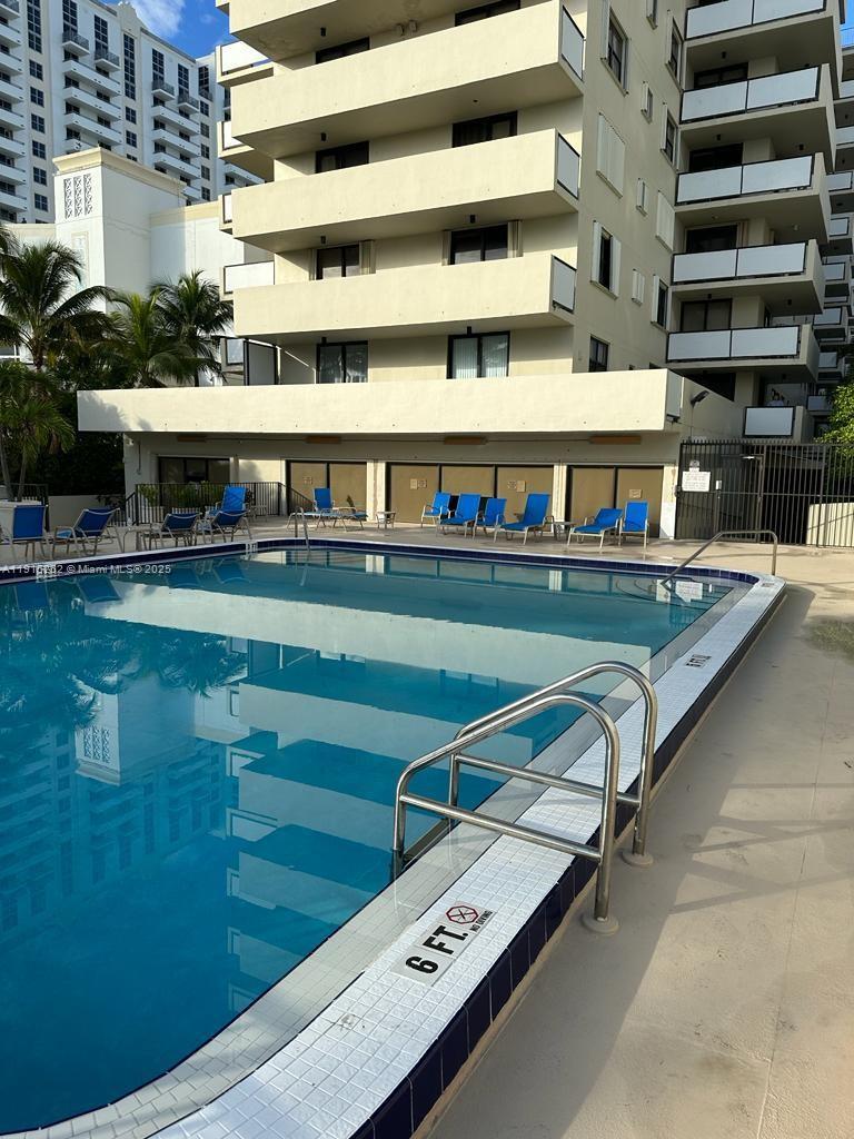 A rectangular swimming pool with a metal ladder sits in front of a multi-story building — 1621 Collins Ave # 505, Miami Beach FL 33139, MIAMI BEACH, FL