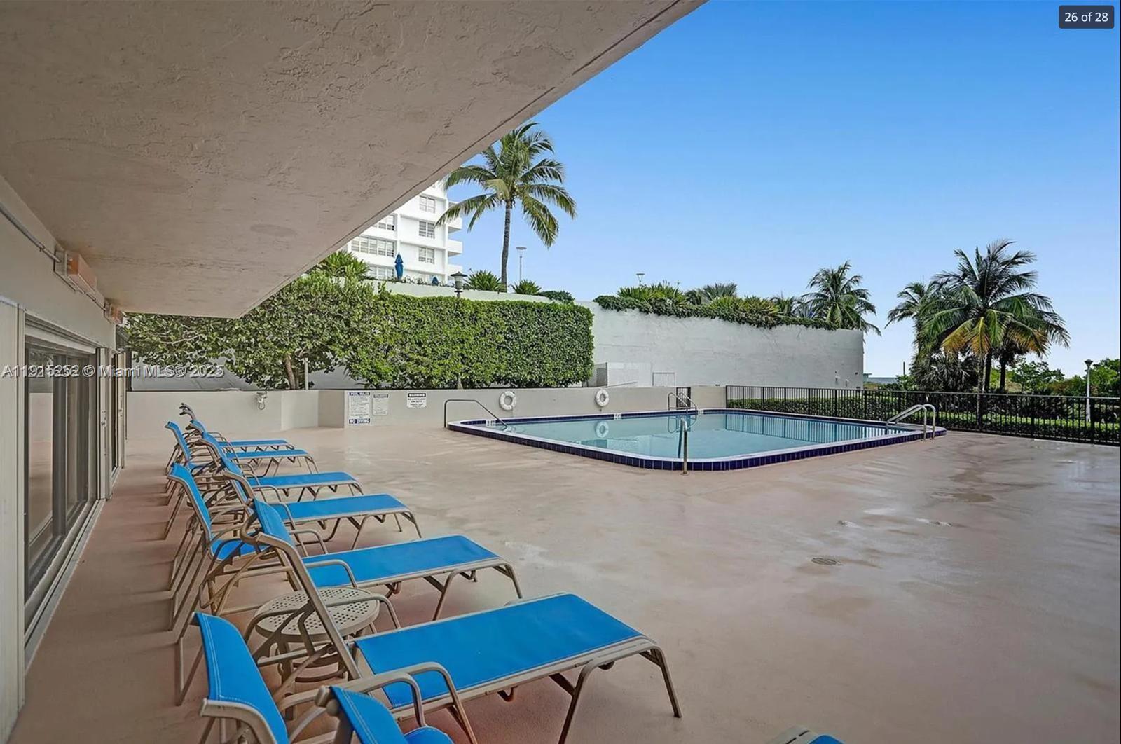 A swimming pool with lounge chairs on a patio under a covered walkway — 1621 Collins Ave # 505, Miami Beach FL 33139, MIAMI BEACH, FL