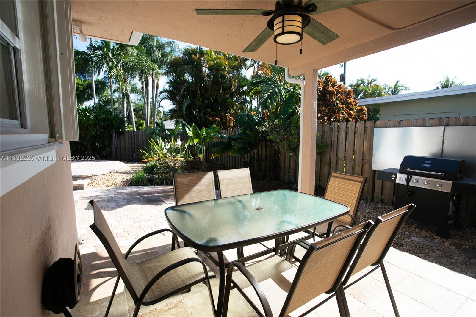 A covered patio features a glass-top dining table, chairs, and a grill in the backyard — 333 SE 3rd Ave, Dania Beach FL 33004, DANIA BEACH, FL