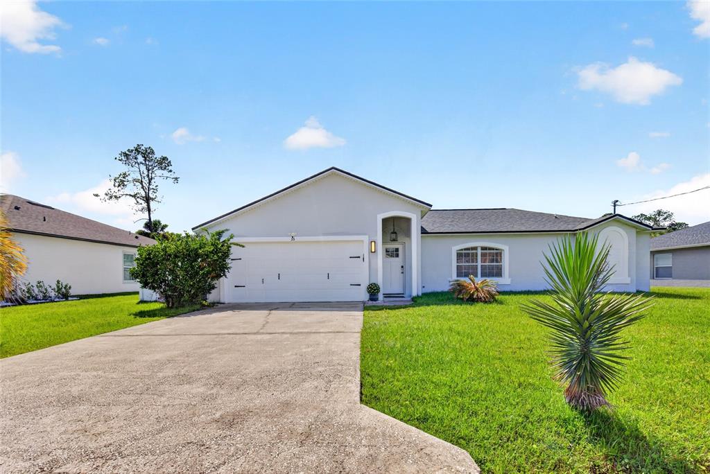 A single-story house with a white exterior, a two-car garage, and a concrete driveway — 33 RIVERSIDE LANE, PALM COAST, FL