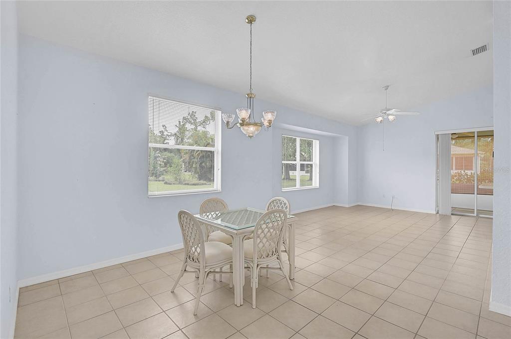 A dining area with tile floors, a glass-top table, and a chandelier under a vaulted ceiling — 1439 MIMS COURT, NORTH PORT, FL