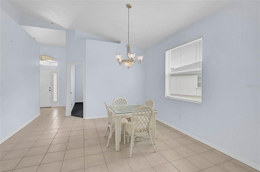 A dining area features light blue walls, tile flooring, a chandelier, and a glass-top table — 1439 MIMS COURT, NORTH PORT, FL