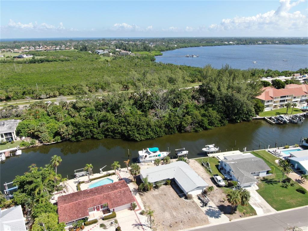 An aerial view shows waterfront homes with docks and boats along a canal near mangroves — 10005 W MANATEE AVENUE W, BRADENTON, FL
