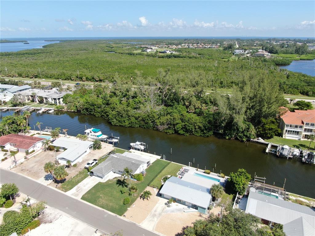 An aerial view shows waterfront homes with private docks along a canal near mangroves — 10005 W MANATEE AVENUE W, BRADENTON, FL
