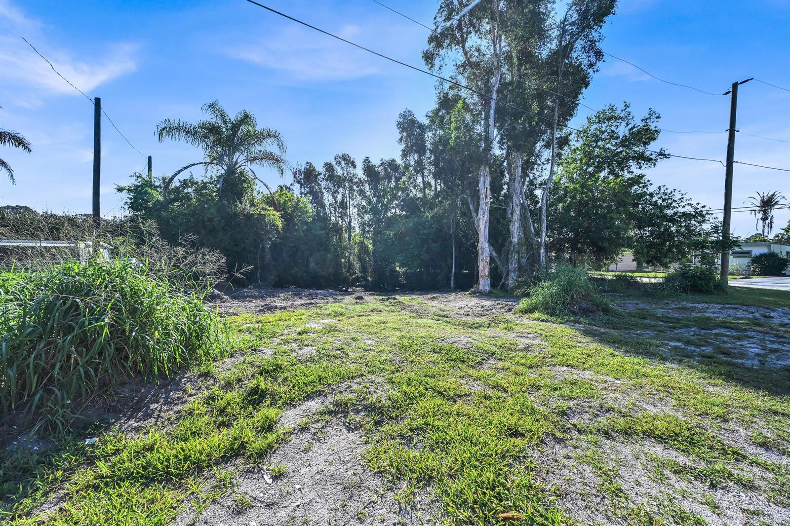 A vacant, grassy lot features scattered trees and power lines under a blue sky — 0 Unassigned, Stuart FL 34997, STUART, FL