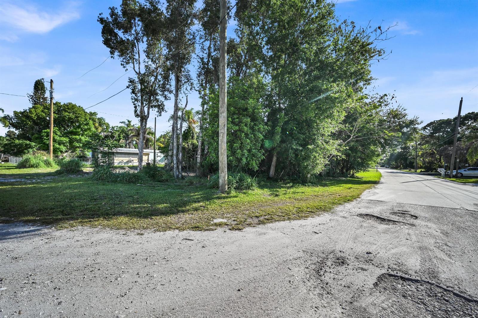 A dirt road leads to a grassy, tree-filled vacant lot under a clear blue sky — 0 Unassigned, Stuart FL 34997, STUART, FL
