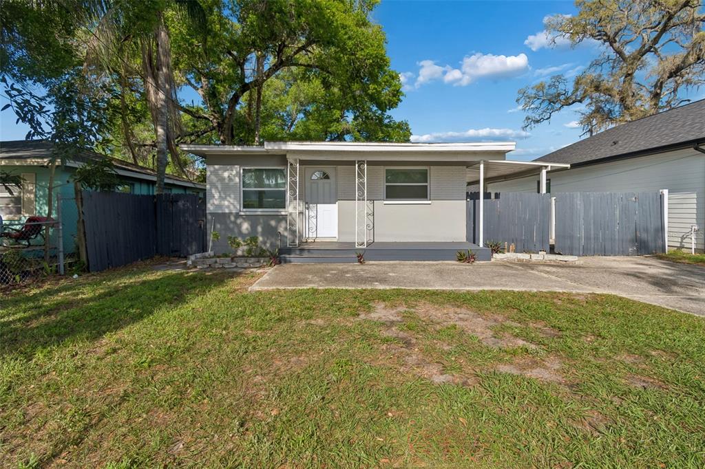 A single-story house with a gray exterior, a front porch, and a concrete driveway — 6710 N HARER STREET, TAMPA, FL