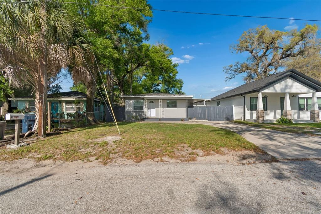 A single-story house with a gray exterior sits between two neighboring homes on a street — 6710 N HARER STREET, TAMPA, FL