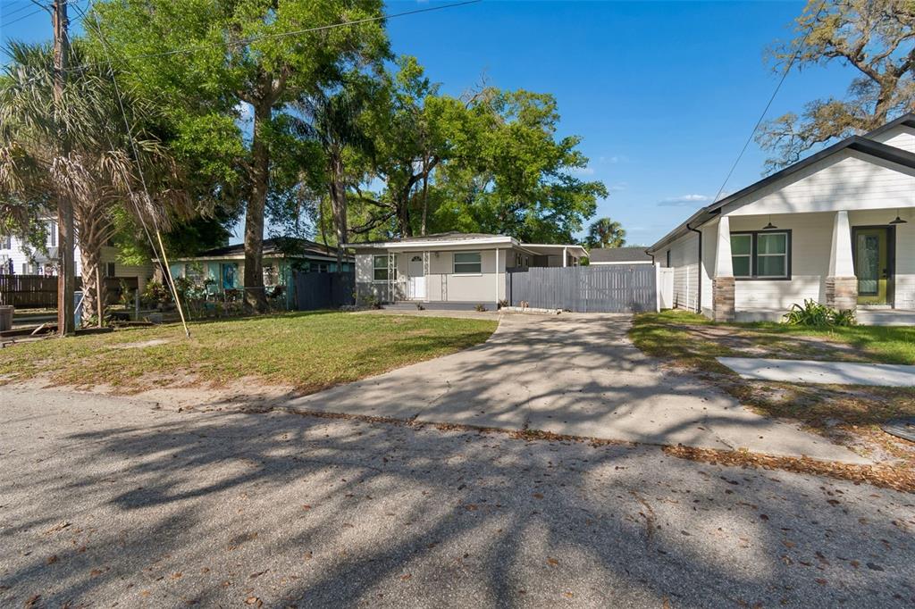 A single-story house with a concrete driveway and a gray fence in a residential neighborhood — 6710 N HARER STREET, TAMPA, FL
