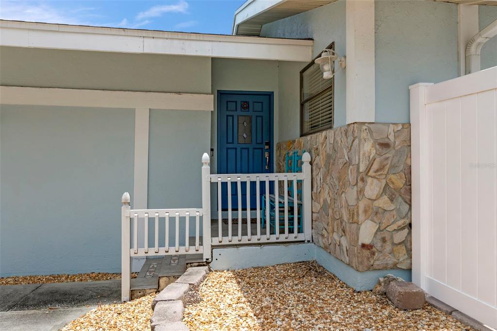 A blue front door is accessed by a small white railing and stone-accented exterior wall — 5250 S RIVERVIEW CIRCLE, HOMOSASSA, FL