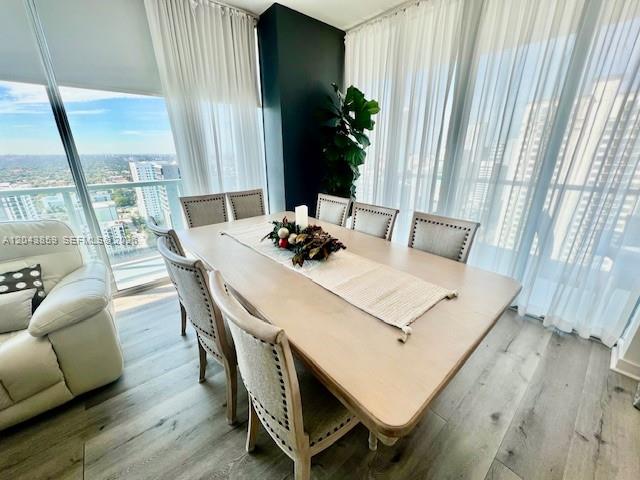 A dining room features a light wood table, upholstered chairs, and floor-to-ceiling windows — 1111 SW 1st Ave # 3225, Miami FL 33130, MIAMI, FL