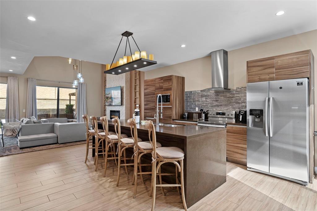 A modern kitchen with wood cabinets, a large island, and stainless steel appliances — 3099 ROCKEFELLER WAY, KISSIMMEE, FL