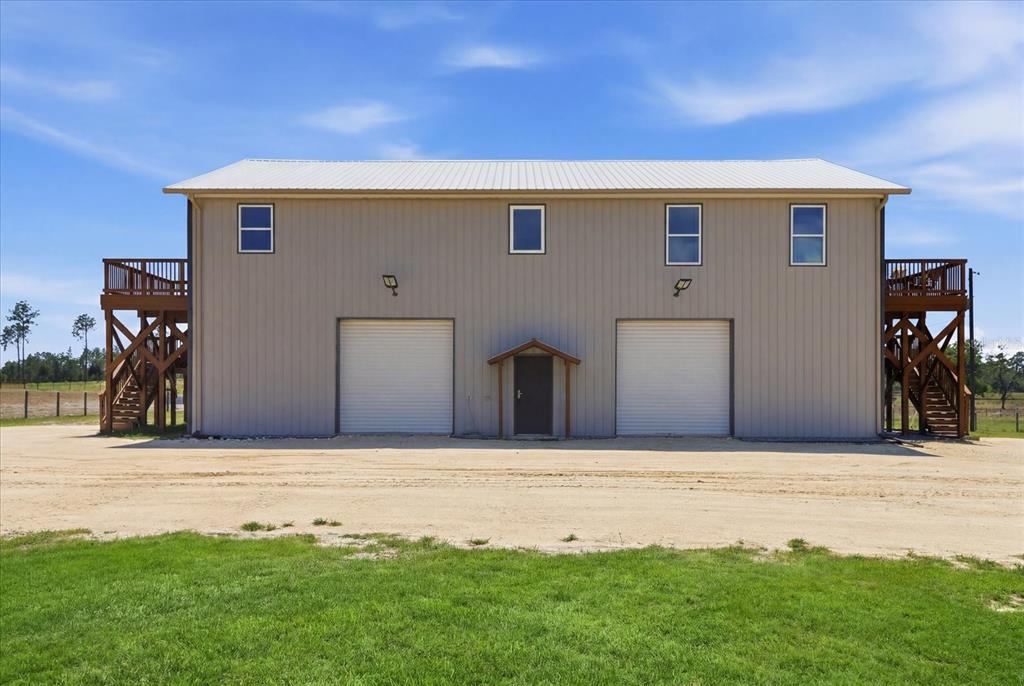 A two-story metal building features two garage doors, a central entrance, and side wooden decks — 9560 N PARKWOOD AVENUE, DUNNELLON, FL