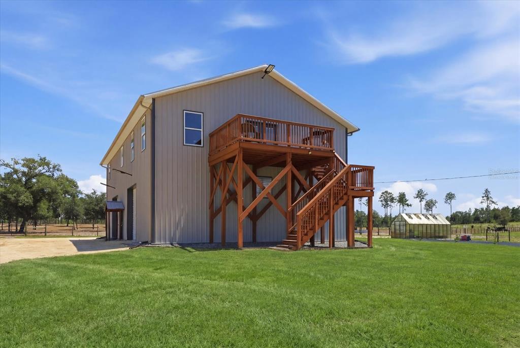 A two-story metal building with a raised wooden deck and staircase in a grassy yard — 9560 N PARKWOOD AVENUE, DUNNELLON, FL