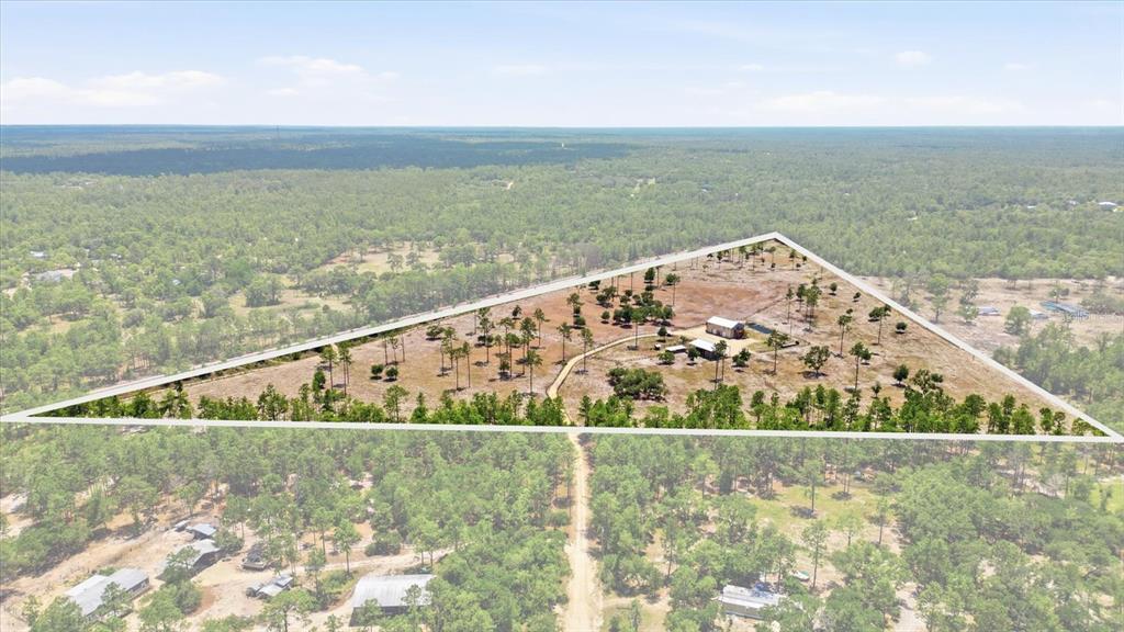 An aerial view shows a triangular plot of land with a barn and scattered trees — 9560 N PARKWOOD AVENUE, DUNNELLON, FL