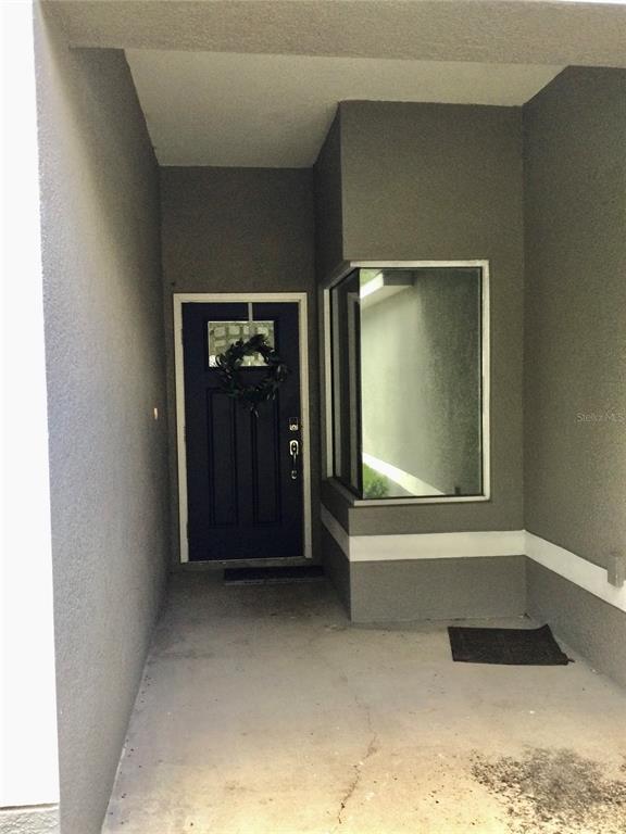 A dark blue front door with a wreath sits in a recessed concrete entryway — 10728 SHADY PRESERVE DRIVE, RIVERVIEW, FL