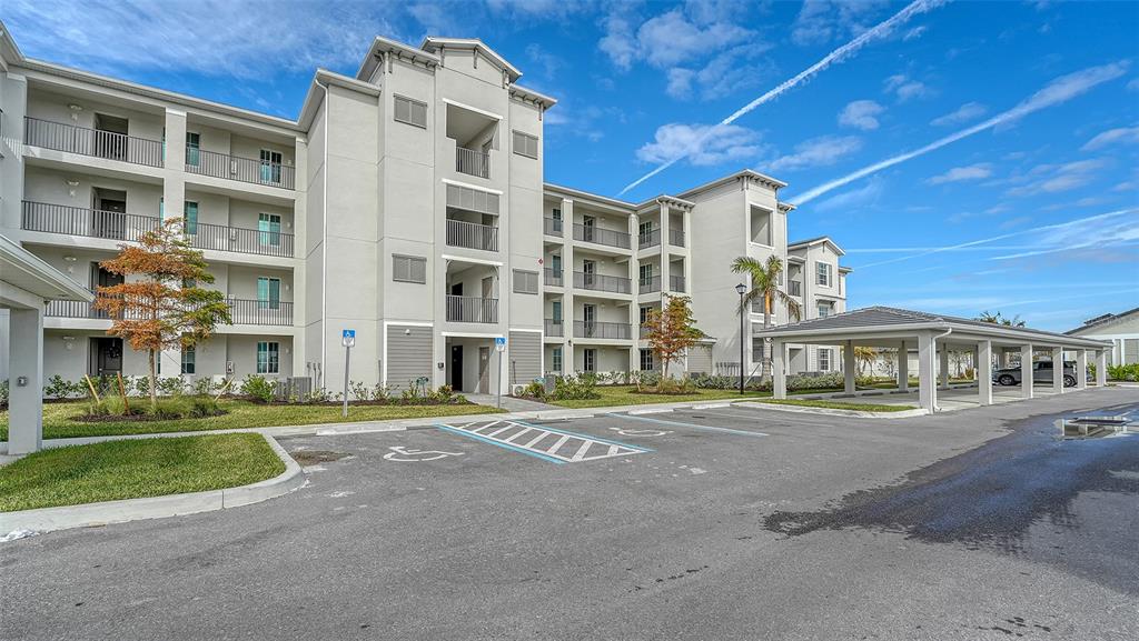 A multi-story apartment building features a parking lot with covered spaces and handicap-accessible spots — 12140 WELLEN GOLF STREET UNIT 307, VENICE, FL