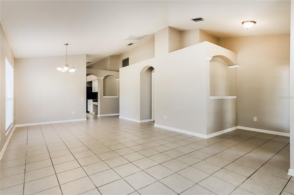An open-concept living area features light-colored tile flooring, arched wall cutouts, and vaulted ceilings — 13302 EVENING SUNSET LANE, RIVERVIEW, FL