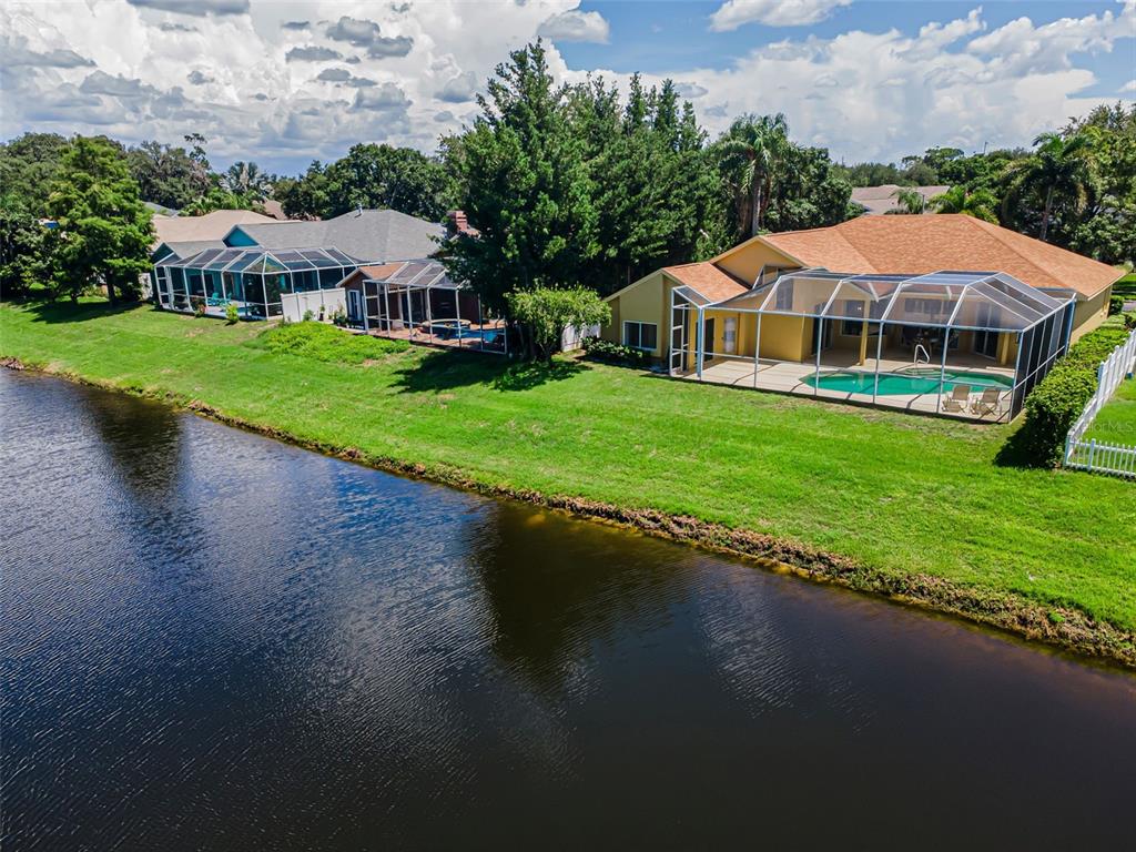An aerial view shows two houses with screened-in pools situated along a waterfront — 1259 PARADISE LAKE DRIVE, TARPON SPRINGS, FL